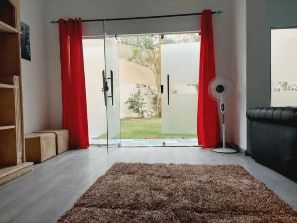 a living room with red curtains and a sliding glass door at 3 Bedroom Apartment with private garden in Sheikh Zayed City Prime location in Sheikh Zayed