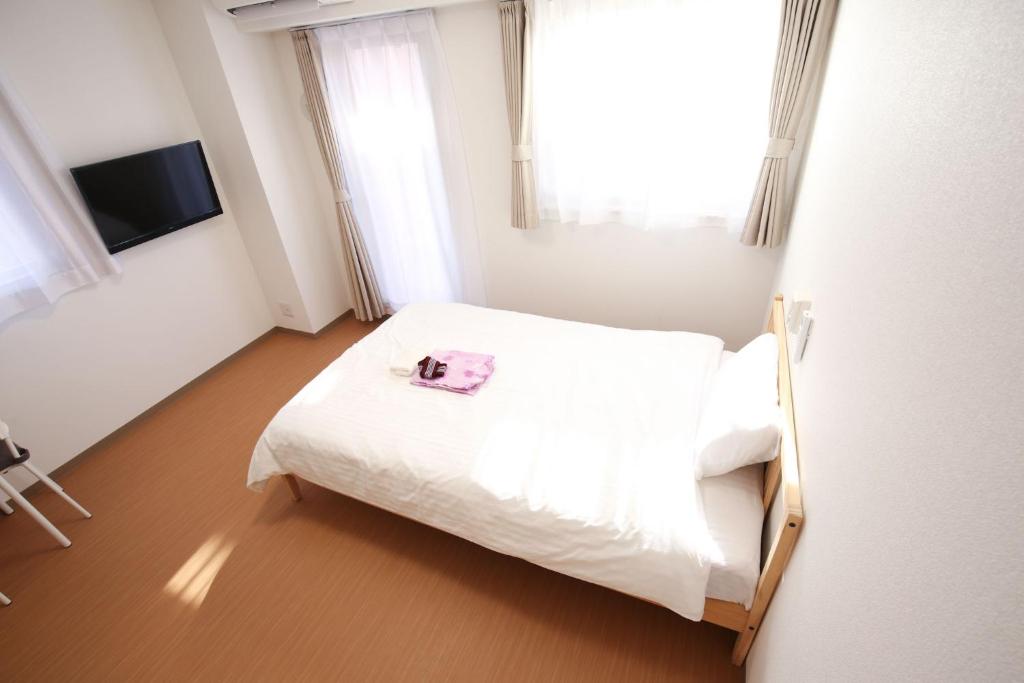 Un dormitorio con una cama blanca con una toalla. en Connect Inn, en Osaka