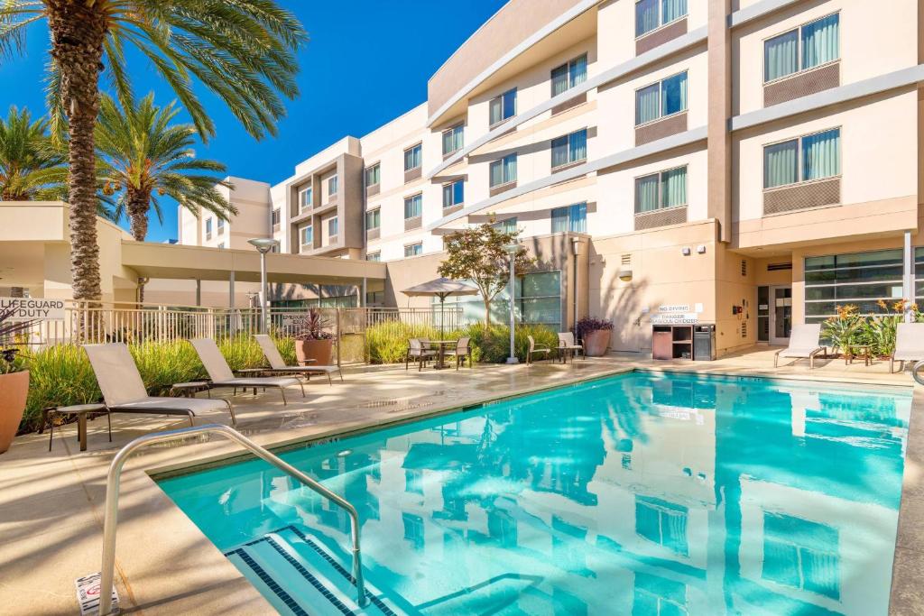 uma piscina em frente a um hotel com palmeiras em Courtyard by Marriott Santa Ana Orange County em Santa Ana