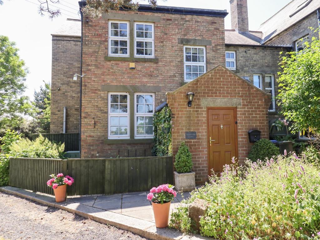 a brick house with a wooden door and a fence at Buzzards Rest in Morpeth