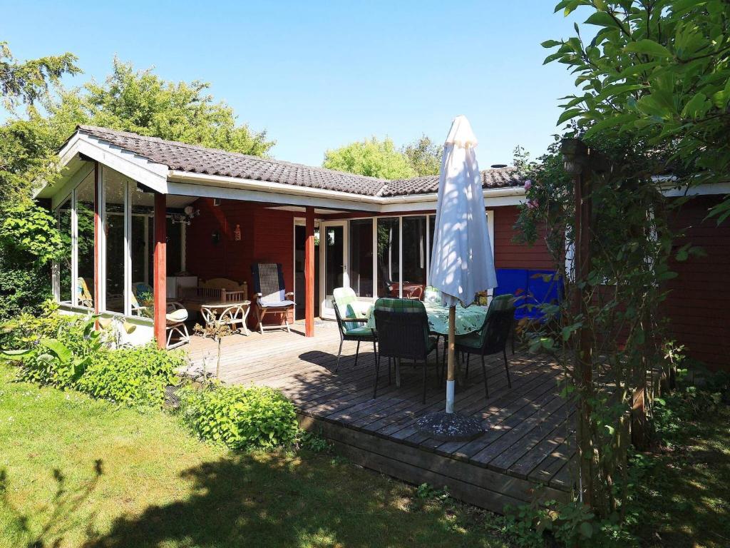 eine Terrasse mit einem Sonnenschirm, einem Tisch und Stühlen in der Unterkunft Holiday home Vordingborg XI in Vordingborg