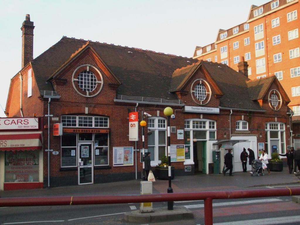 a brick building with people walking in front of it at Nice and Pleasant in Thornton Heath