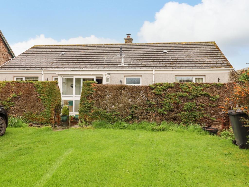 a house with a hedge in front of a yard at New Cottage in Wooler