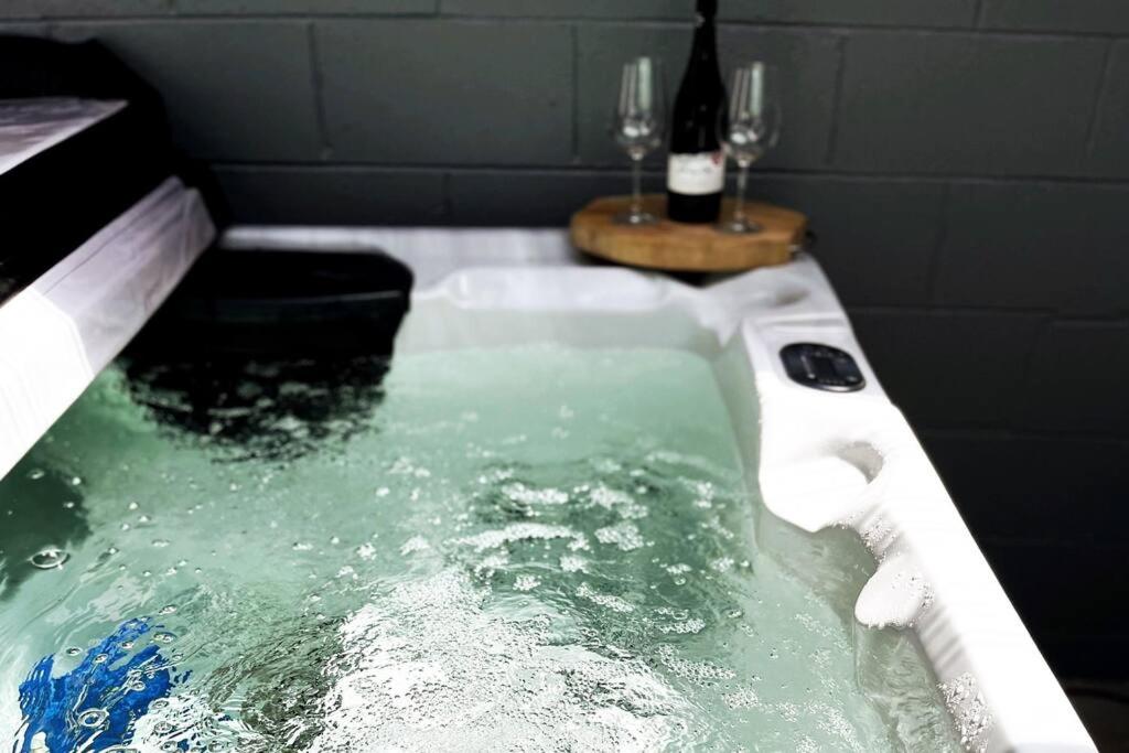 a bath tub filled with water with two wine glasses at T Two on Whakaue in Rotorua