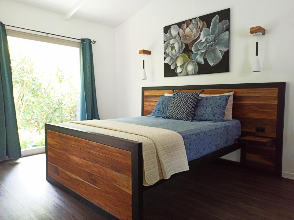 1 dormitorio con 1 cama con cabecero de madera y ventana en Chilamate Holiday House, en Puerto Viejo