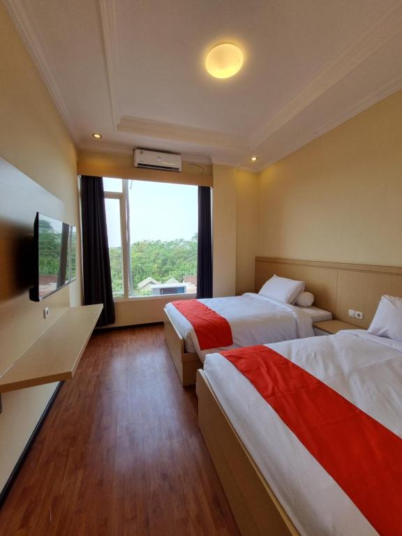 um quarto de hotel com duas camas e uma grande janela em core inn juwita hotel em Kepanjen