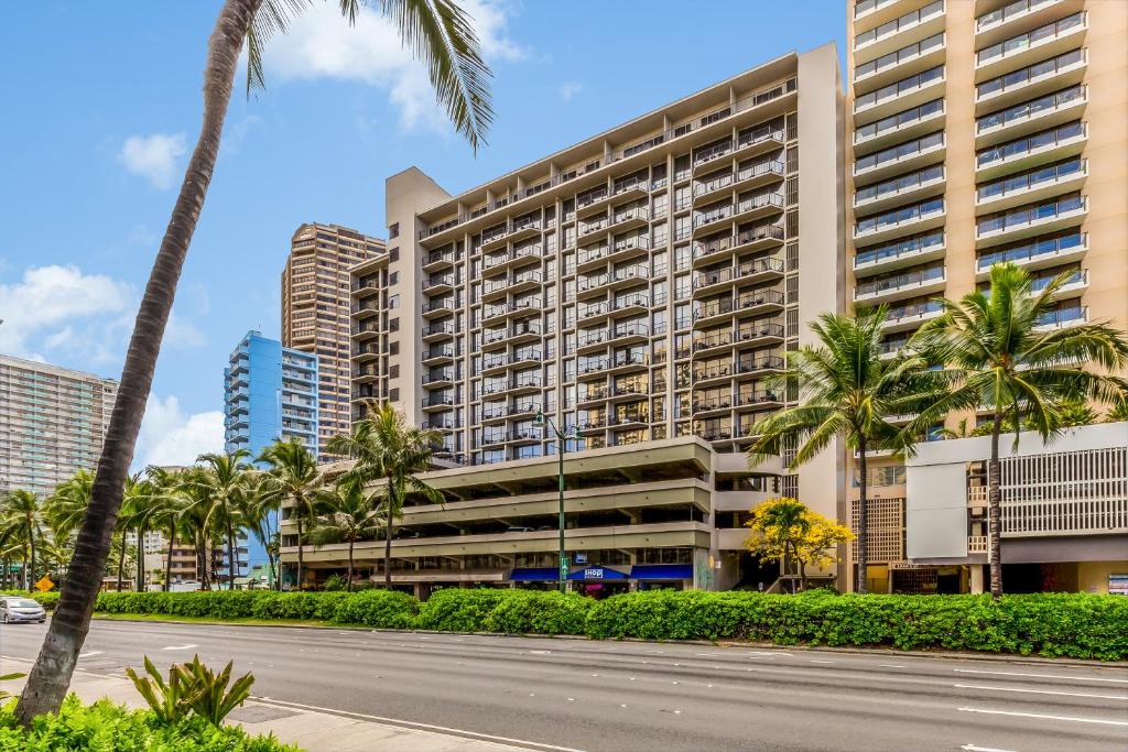 CASTLE at Palms at Waikīkī في هونولولو: مبنى كبير فيه نخل قدام شارع