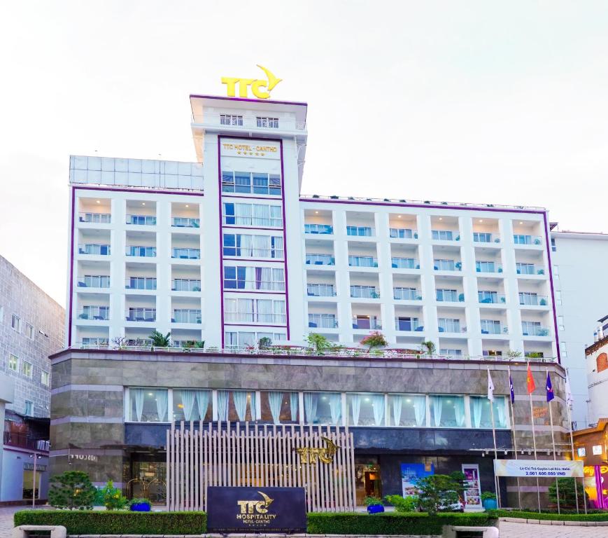 Un grand bâtiment blanc avec un panneau en haut dans l'établissement TTC Hotel - Can Tho, à Cần Thơ