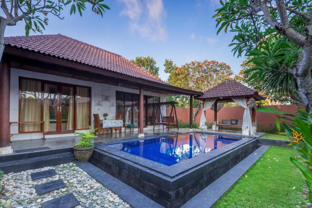 a villa with a swimming pool in front of a house at Lavender Villa & Spa in Kuta