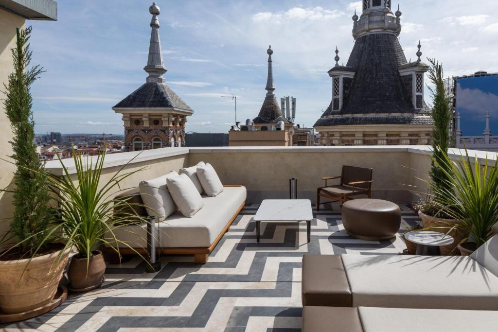 a rooftop patio with a couch and tables on a building at JW Marriott Hotel Madrid in Madrid