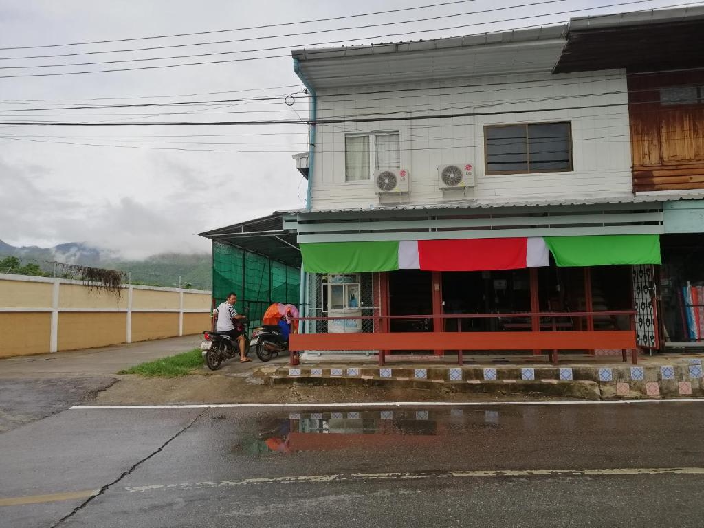 un edificio con dos personas en motocicleta delante de él en Lungmin homestay, en Mae Hong Son