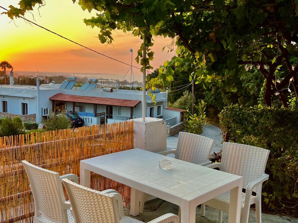 uma mesa branca e cadeiras com o pôr-do-sol ao fundo em Greek House Tatiana em Cós