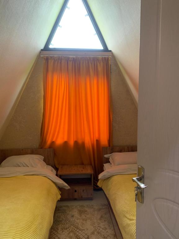 Cette chambre mansardée comprend 2 lits et une fenêtre. dans l'établissement Hillside Borjomi, à Bordjomi