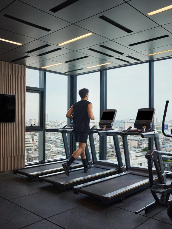 A gym cardio area with treadmills facing a broad city view.