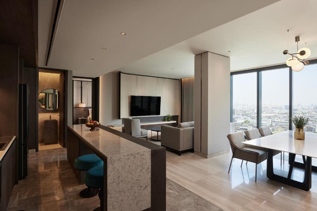 An open-plan suite with a kitchen counter, dining table, lounge and city view.