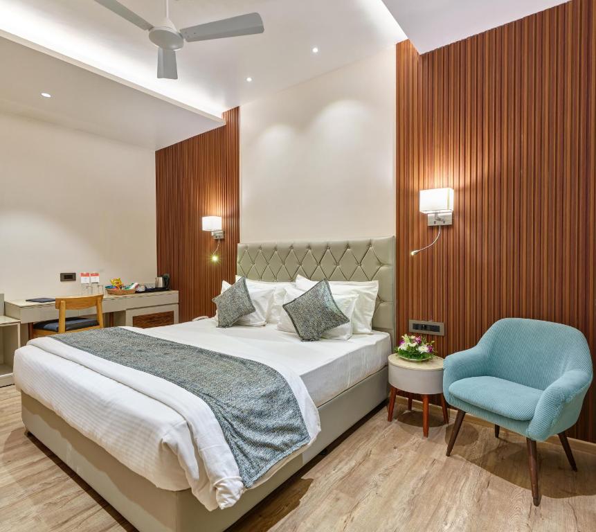 a bedroom with a bed and a blue chair at Regenta Place Raysons Kolhapur in Kolhapur