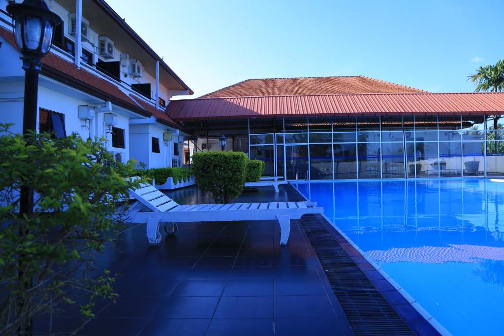 a swimming pool with benches next to a building at PJ Hotels Jaffna in Jaffna