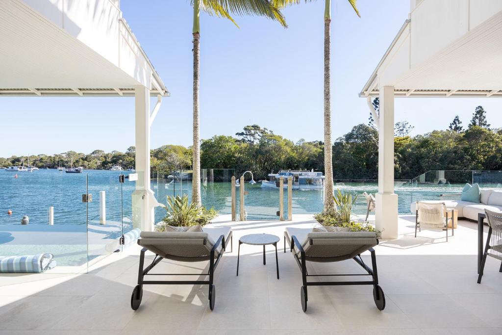 a patio with a table and chairs next to the water at 12 Noosa Parade, Noosa Heads in Noosa Heads