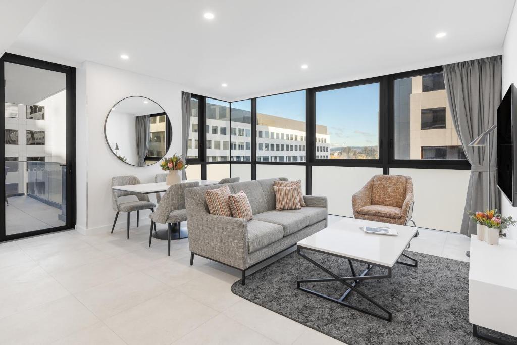sala de estar con sofá, sillas y mesa en Meriton Suites Canberra, en Canberra