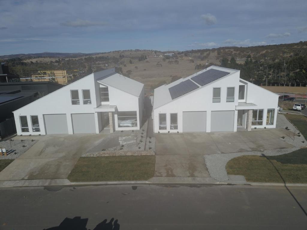 een huis met twee witte huizen op een oprit bij Powder Peaks in Jindabyne