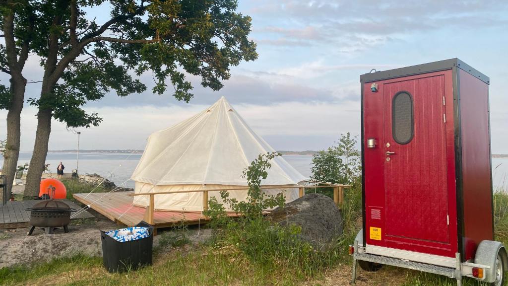 a tent and a trailer next to a lake at Aspö Glamping in Drottningskär