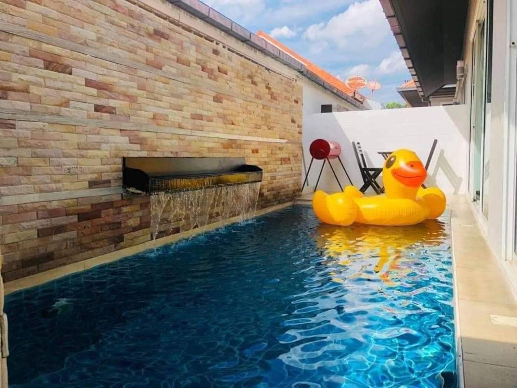 ジョムティエンビーチにあるFeel Like Home Pool Villa Pattayaのレンガの壁の前にゴムダックが置かれたプール