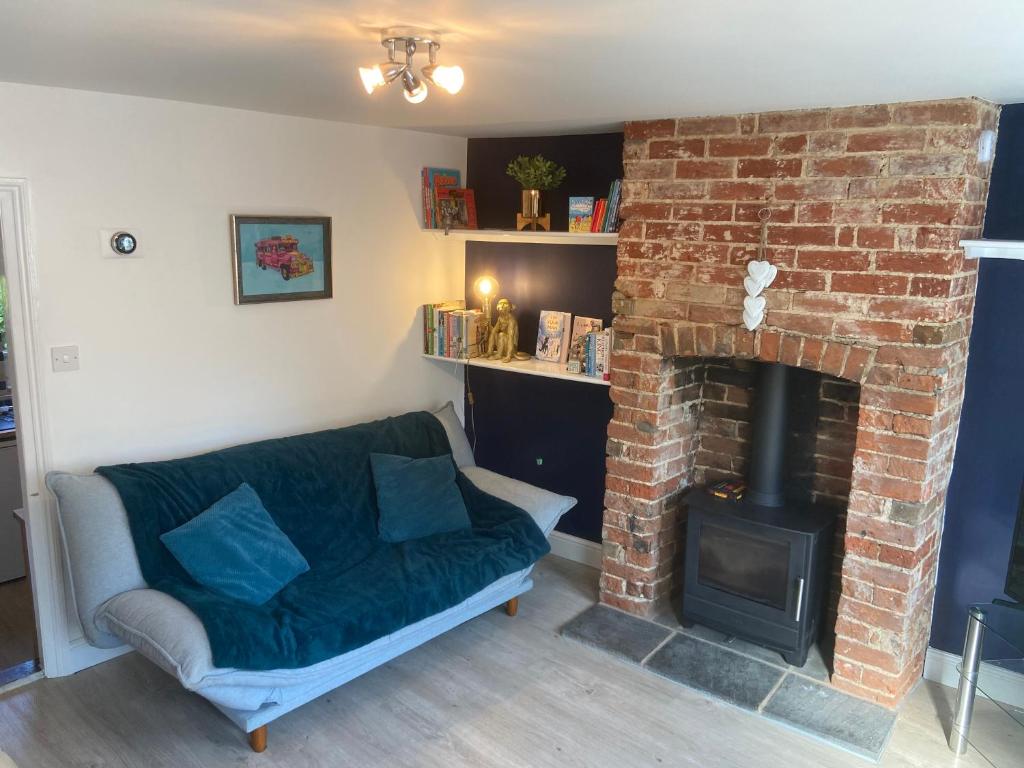 a living room with a couch and a brick fireplace at Woodbridge - Cosy little 2-Bed Cottage in Woodbridge