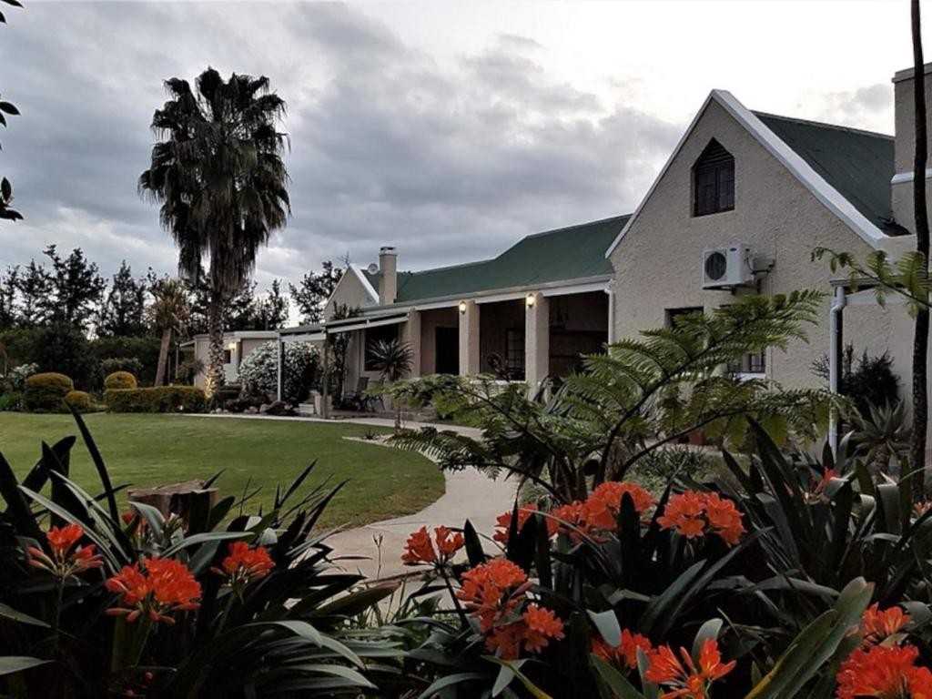 une maison blanche avec des fleurs orange devant elle dans l'établissement Silos Guesthouse, à Addo