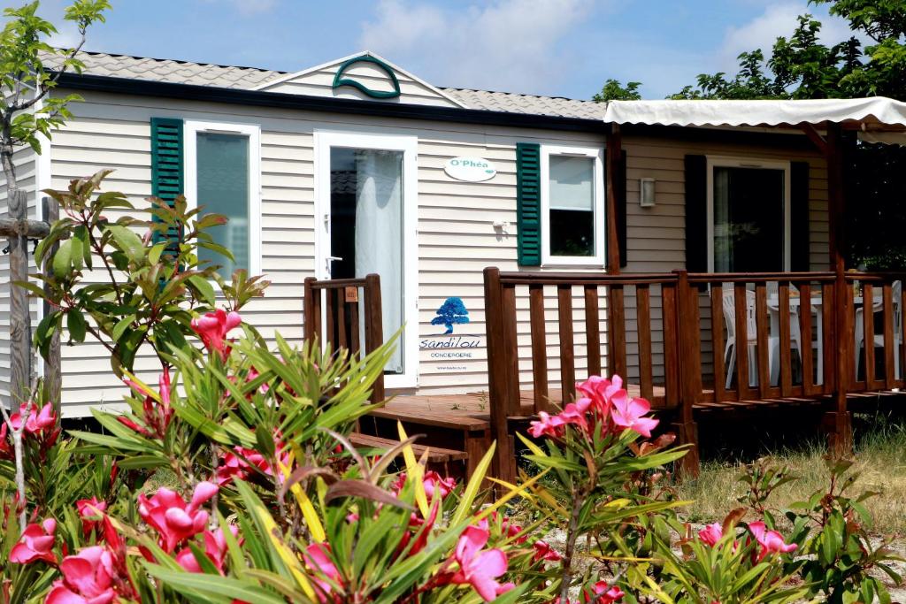 a tiny house with a porch and flowers at Mobilhome «des Salines» * 6 personnes *3 Chambres in Sigean
