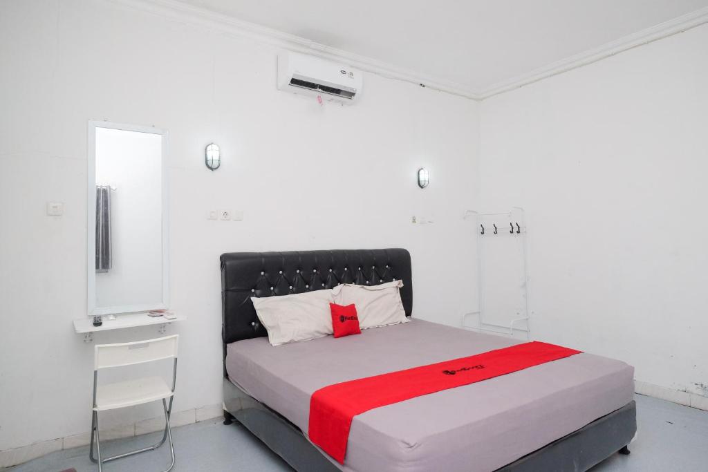 a white bedroom with a bed with a red blanket at RedDoorz Syariah at Griya Merbotan Demak in Demak