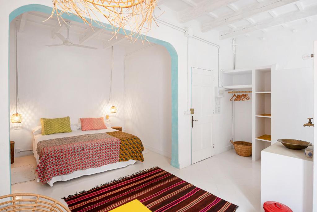 a white bedroom with a bed and a rug at La Cayena Rooms in Ciutadella
