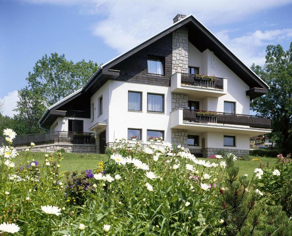 a white house with flowers in front of it at pension Jesen in Benecko