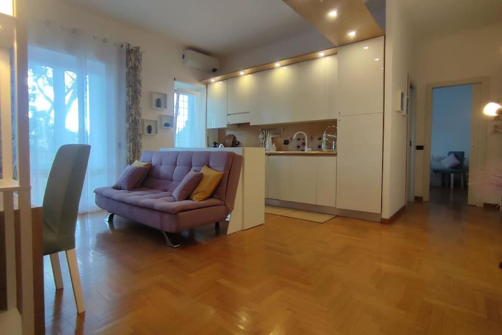 a living room with a purple couch and a kitchen at Gastaldi House, EUR Mostacciano, delizioso flat in Rome