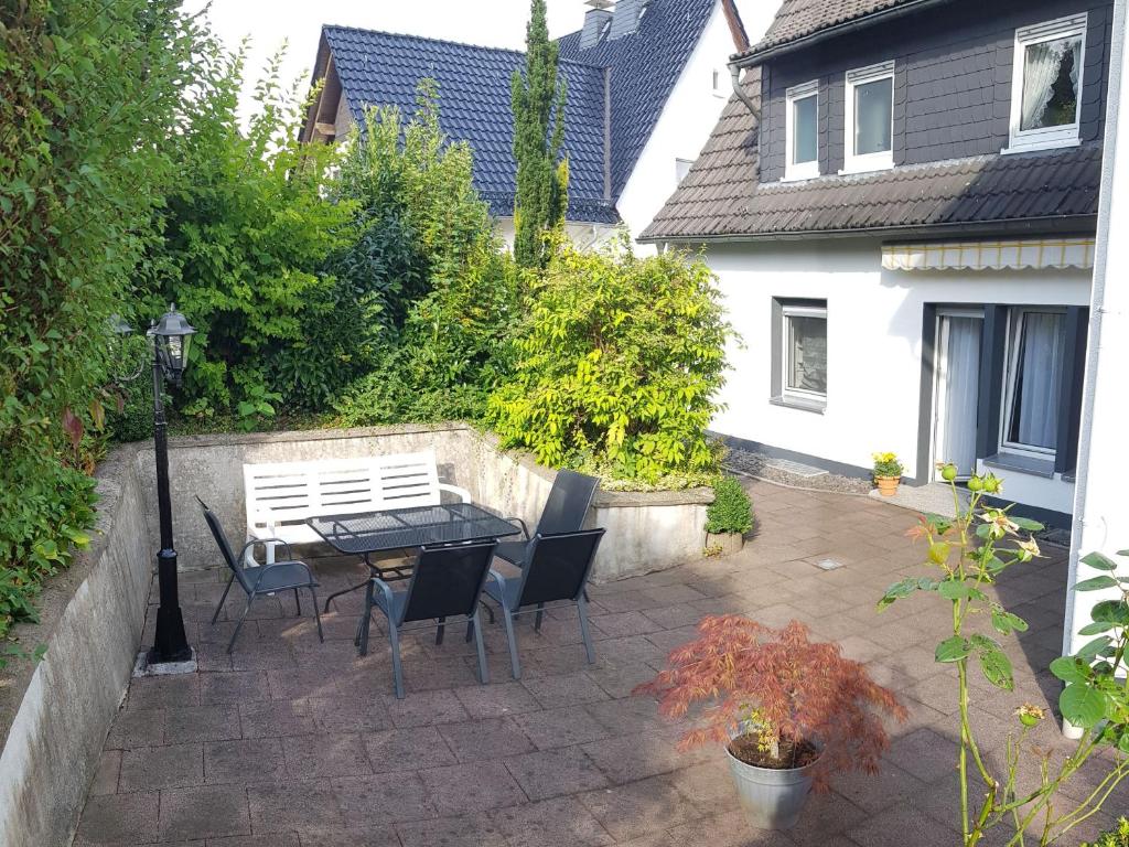 un patio con mesa, sillas y banco blanco en Ferienwohnung Oerder, en Meinerzhagen
