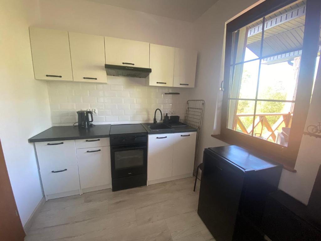 a small kitchen with white cabinets and a window at Brzozowe Wzgórze z jacuzzi i rowerami in Jastrzębia Góra