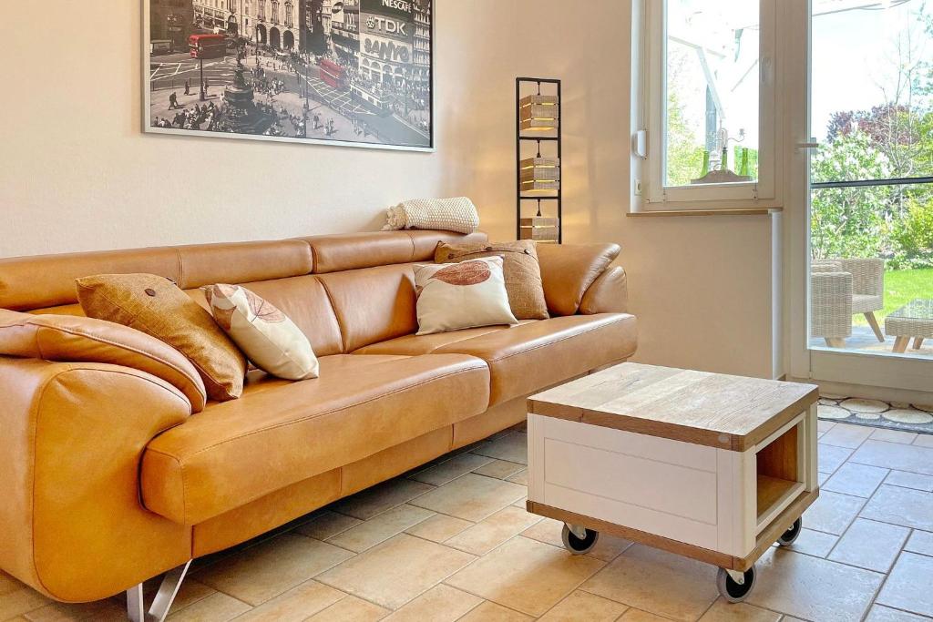 un sofá de cuero marrón en una sala de estar con mesa en Ferienwohnung Am Park, en Lübbenau