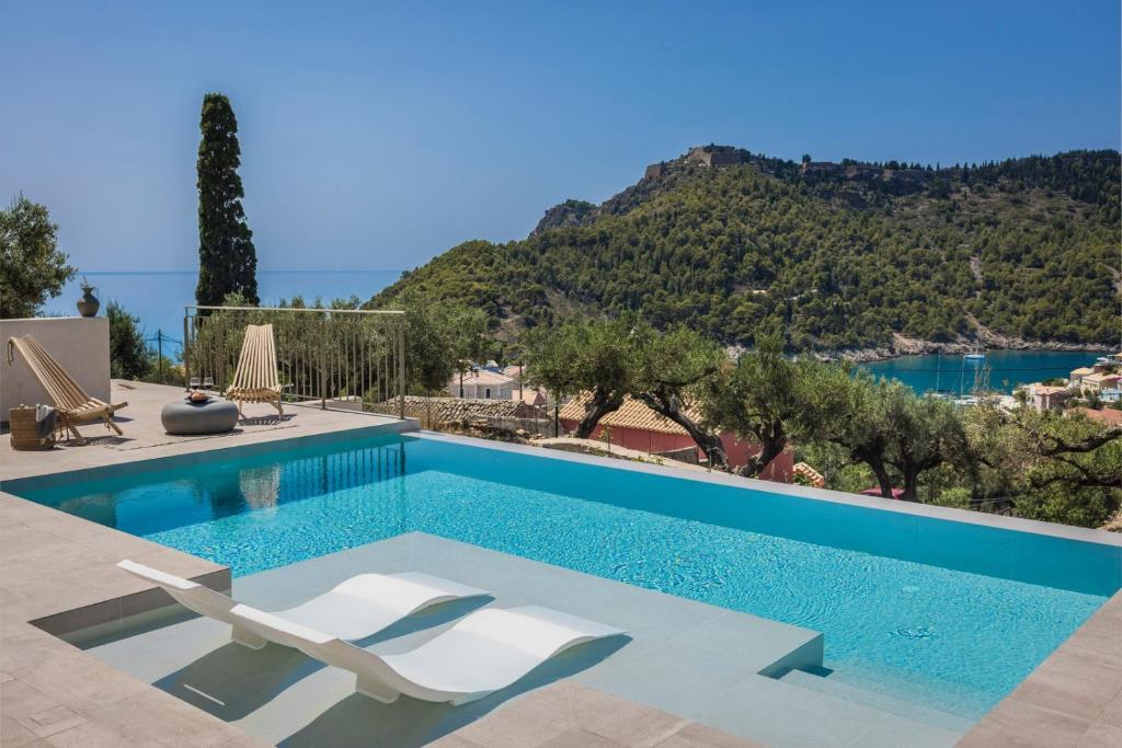 a swimming pool with two chairs and a view of a mountain at Lanolia - Olea Di Assos Villas in Asos