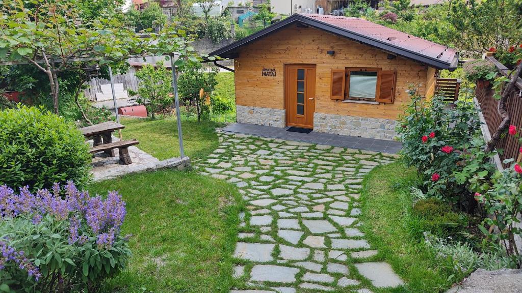 a small wooden cabin in a garden with a stone path at Apartma Mataj in Kobarid