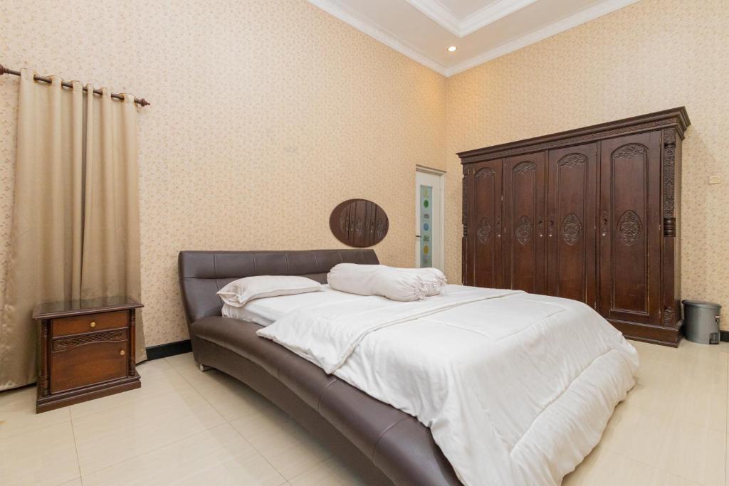 a bedroom with a large bed with a wooden headboard at Boss Residence Serang Mitra RedDoorz in Kumprung
