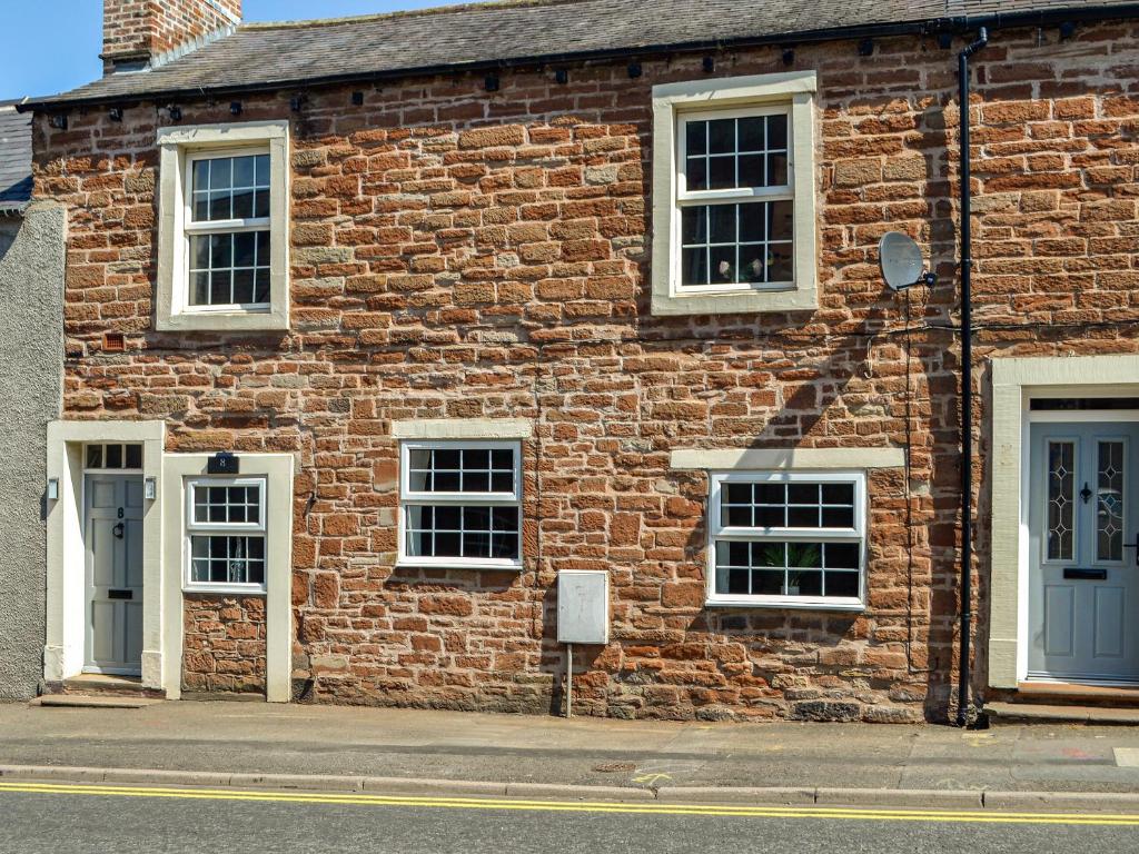 a brick building with white windows and blue doors at Constable Cottage in Brampton