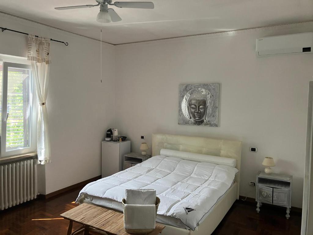 una camera bianca con un letto e un ritratto sul muro di Villa Mariel - Adults Only Giannella Playa a Orbetello