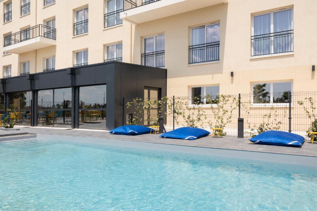 een hotel met een zwembad voor een gebouw bij Ibis Styles Miramas in Miramas