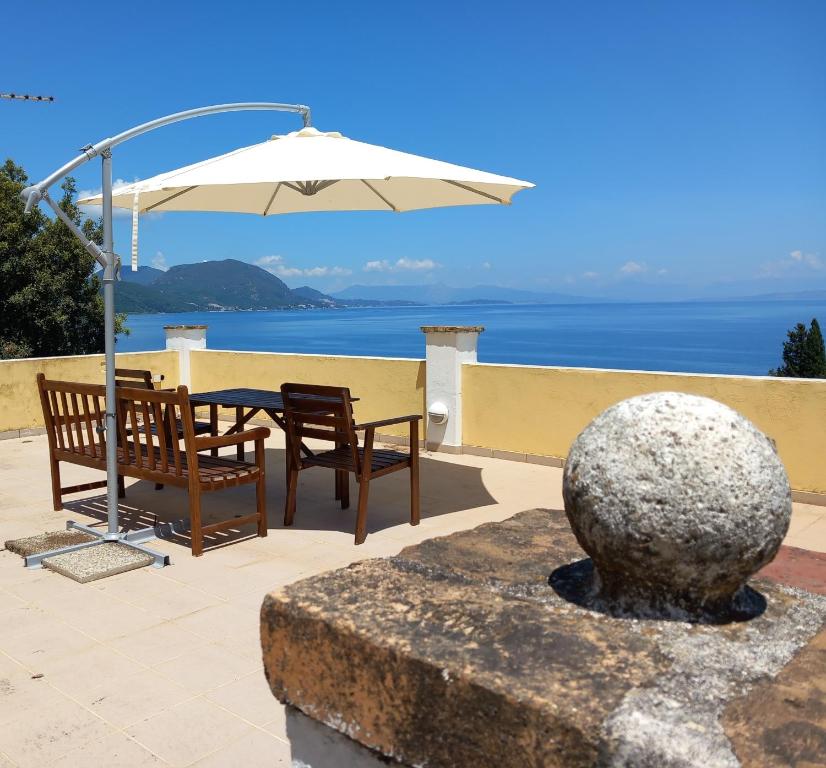 un patio con sombrilla, mesa y sillas en Olea Home en Agia Pelagia Chlomou