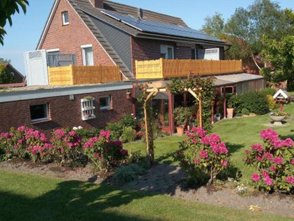 una casa con flores rosas en el patio en NEU ! FEWO Deichblick 1 OG en Dornum