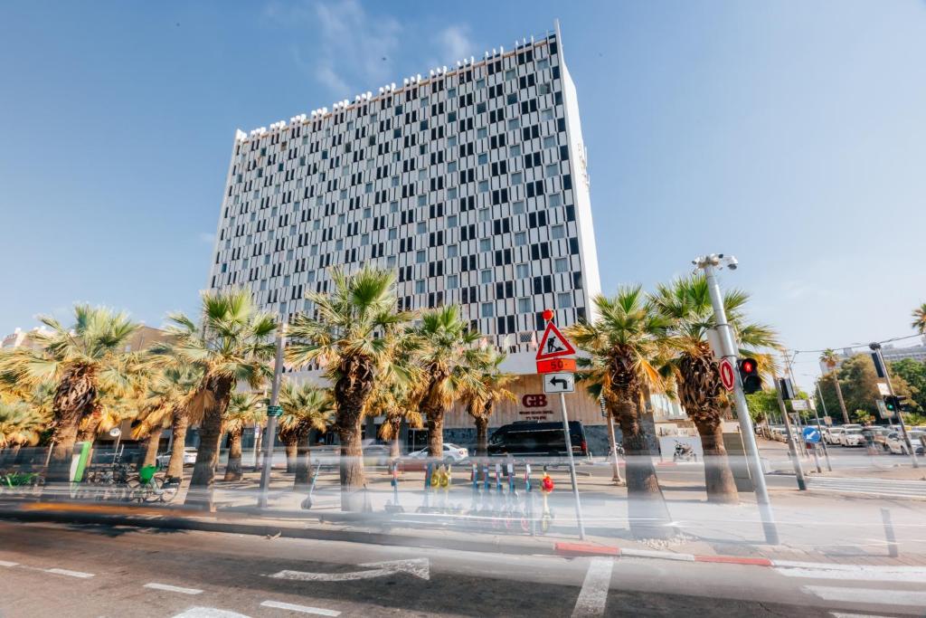 a tall building with palm trees in front of it at Grand Beach Hotel in Tel Aviv