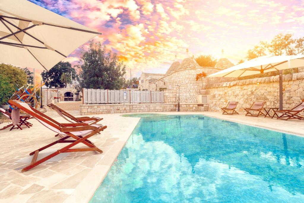 a swimming pool with two chairs and an umbrella at Navolte Trulli e Quiete in Locorotondo