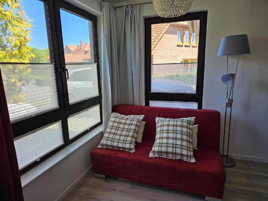 BarsbekにあるFerienwohnung zwischen Laboe und Schönbergの窓のある部屋に、枕が2つ置かれた赤いソファ