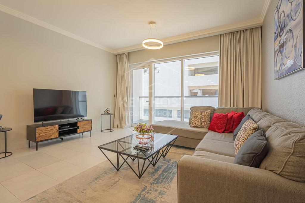 a living room with a couch and a television at KeyHost - Large 1BR Apartment near Five Hotel JVC - Dubai - K310 in Dubai