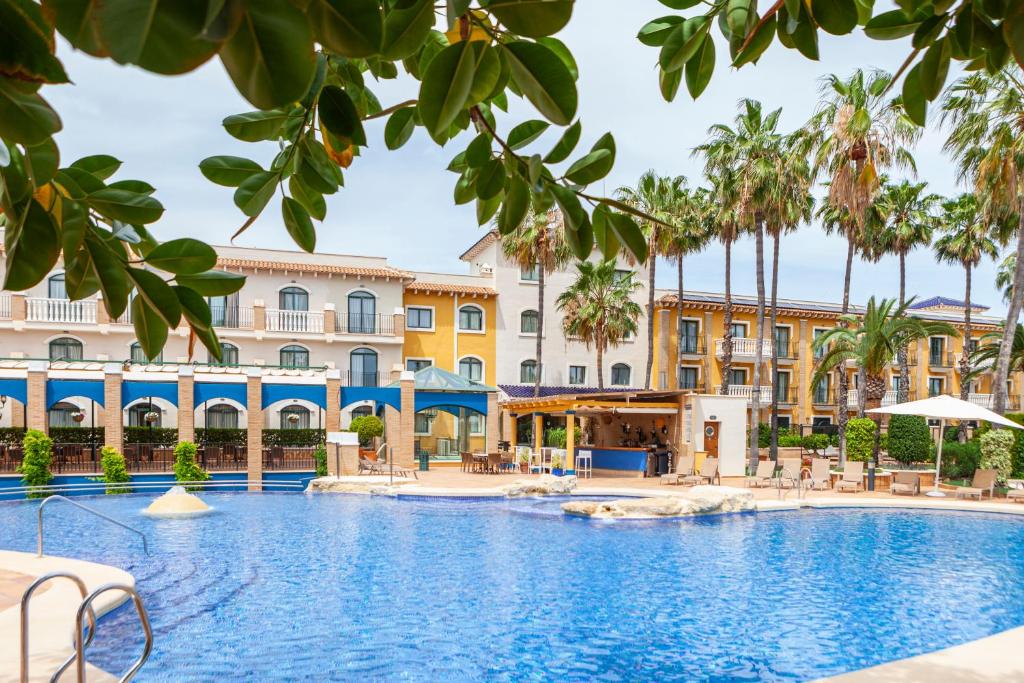 a pool in front of a hotel with palm trees at Hotel La Laguna Spa & Golf in Torrevieja