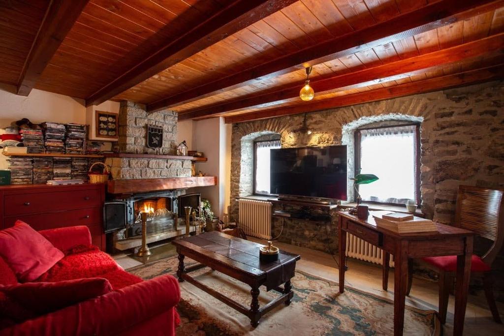 sala de estar con sofá, mesa y TV en Castello di Darany,dimore con spa private con Jacuzzi e saune, en Villeneuve